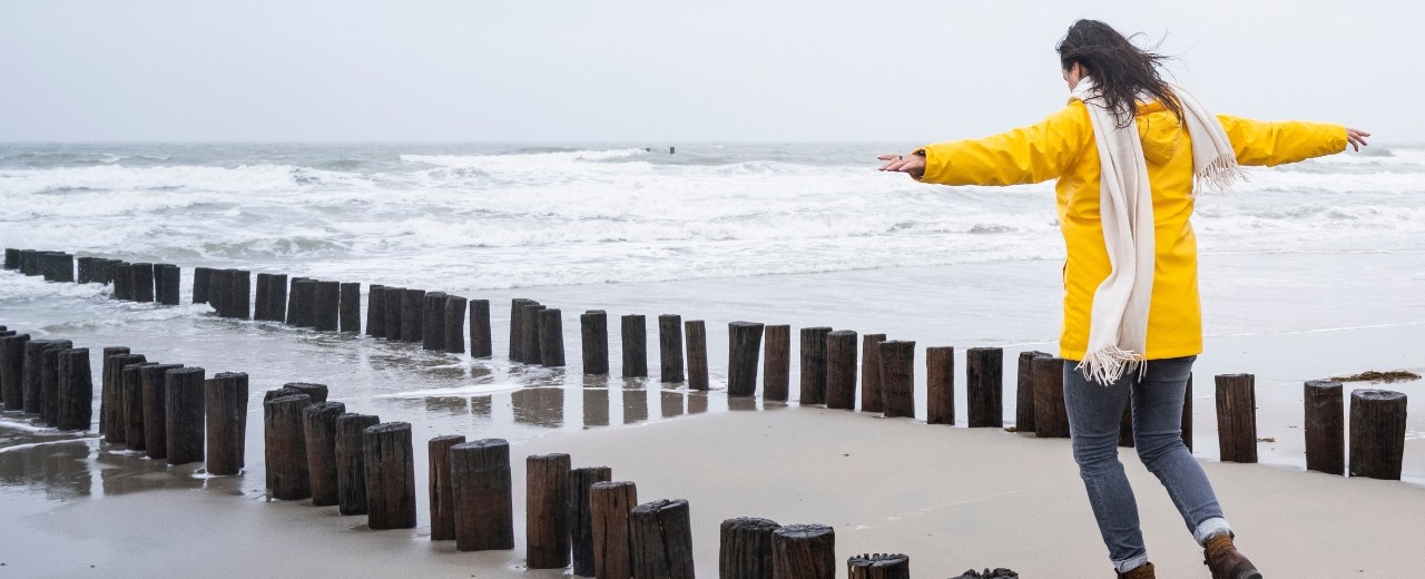 Vrouw balanceert op paaltjes bij zee